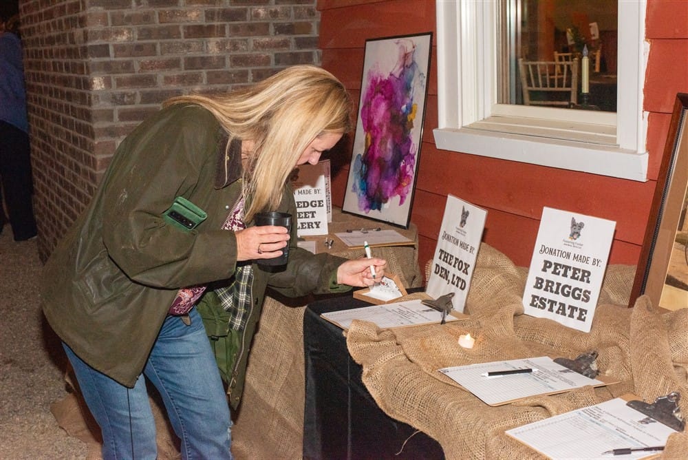 Guest bidding on a silent auction item at the Fostering Foster Barn Dance